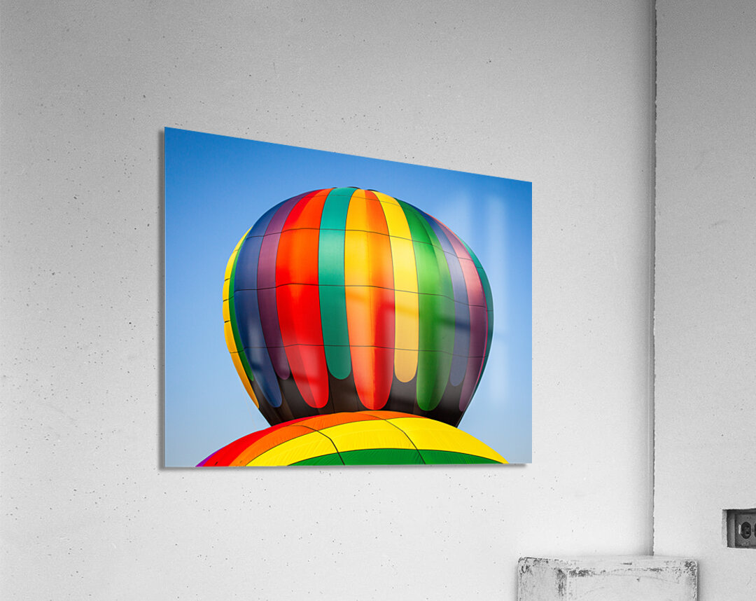 Colorful hot air balloon rising above another with blue sky Acrylic Print