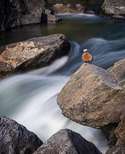 Pebbles balanced on rocks in raging river illustrating resilienc