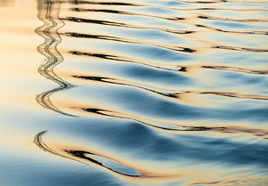 Reflections of electricity pylon at sunset in gentle river rippl