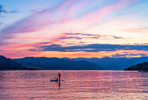 Sunset over Lake Chelan with silhouette of couple paddling on pa Print