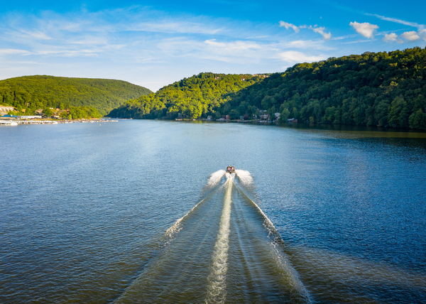Speedboat on Cheat Lake on a summer evening with boats docked in by Steve Heap