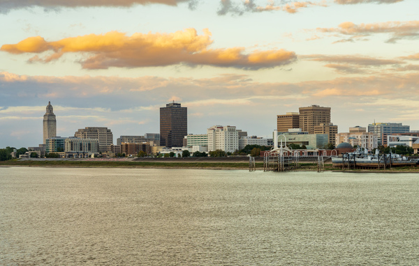 Skyline of Baton Rouge at sunset over river barges by Steve Heap