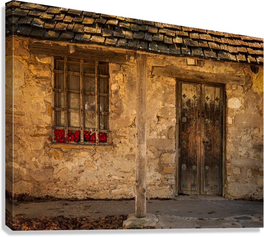 Rustic San Juan building with a barred window red flowers and a Canvas Print