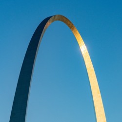 Unusual view of Gateway Arch at sunrise against blue sky