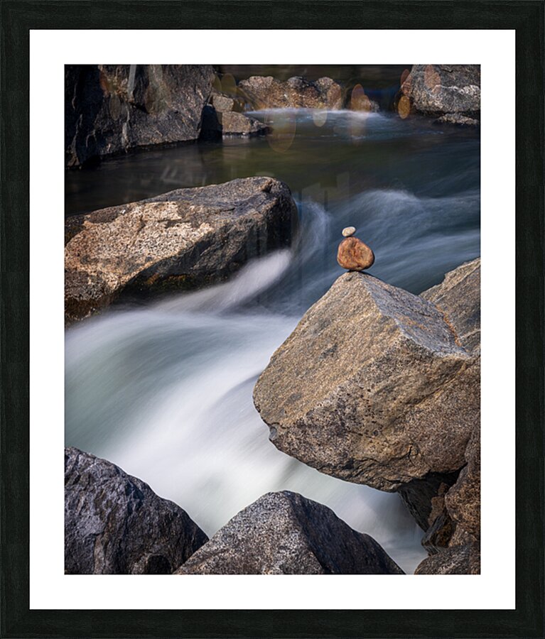 Pebbles balanced on rocks in raging river illustrating resilienc Picture Frame print