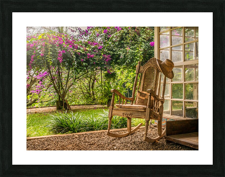 A vintage wooden rocking chair with a straw hat rests on a porch Picture Frame print