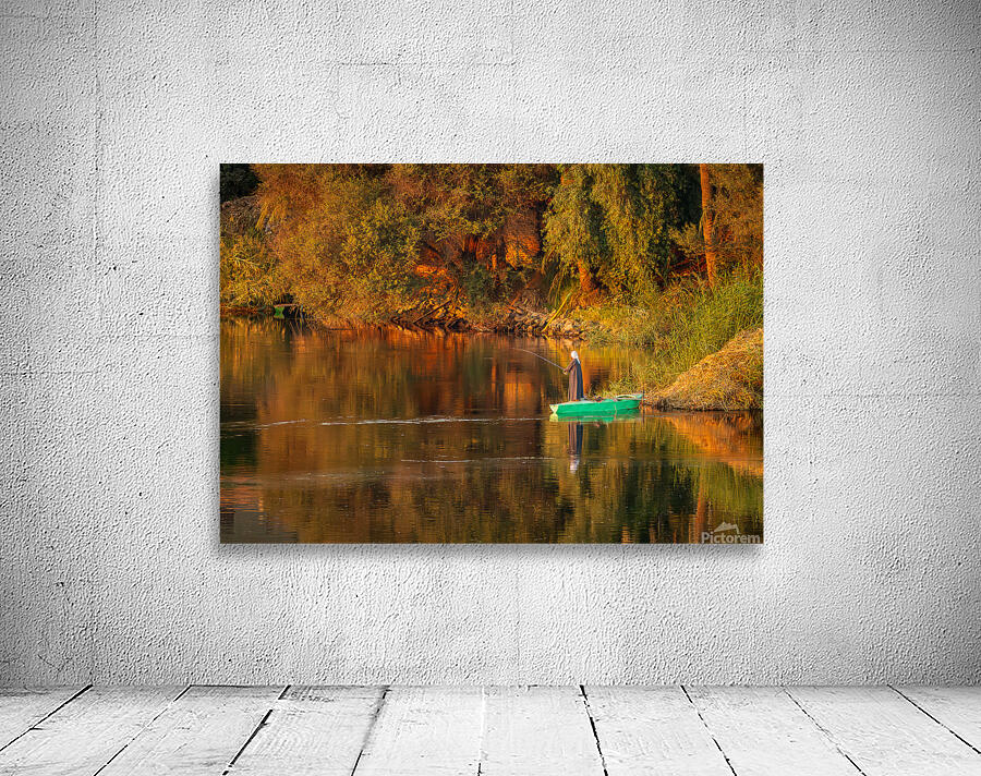 Man in traditional galabia fishing from small boat on river Nile Wall Preview
