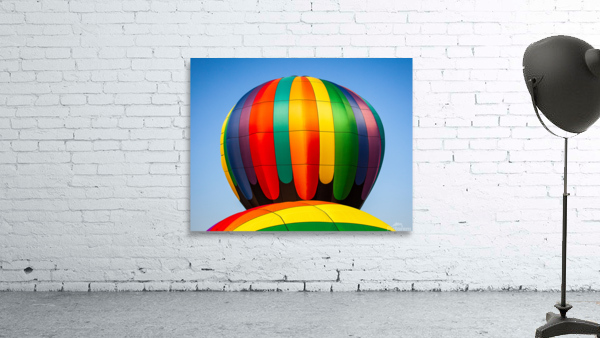 Colorful hot air balloon rising above another with blue sky by Steve Heap